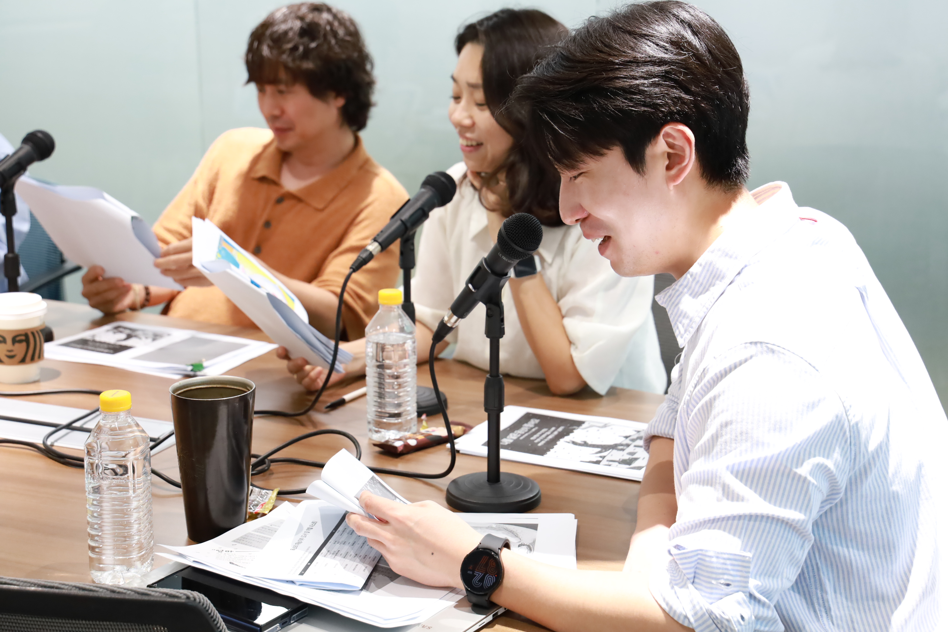 신세계아이앤씨 임직원들이 목소리 기부 봉사 활동에 참여하고 있다. 마이크 앞에서 동화책을 읽고, 녹음하고 있는 모습